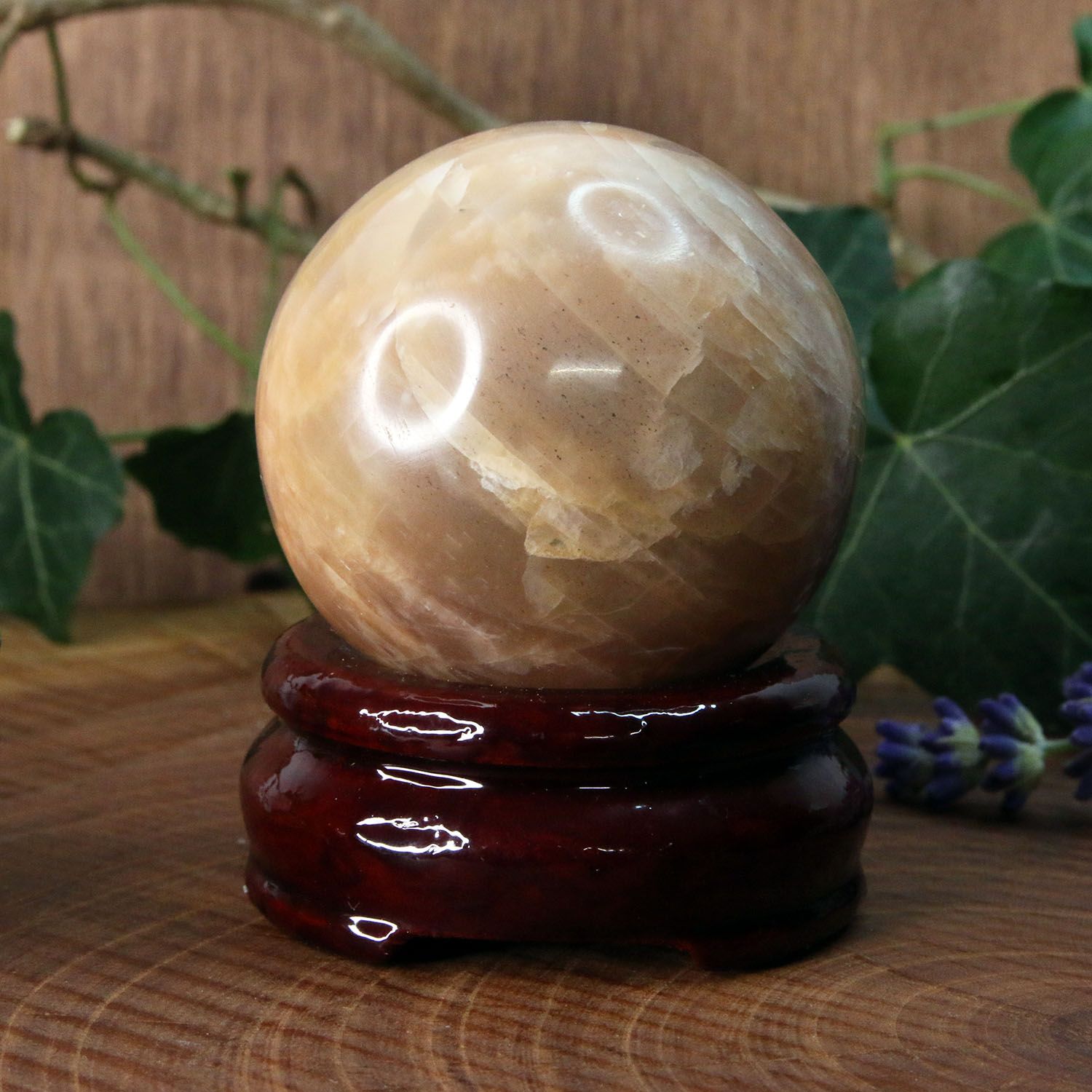 Pierre de lune orange sphérique sur son socle en bois
